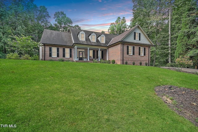 cape cod home with a porch and a lawn