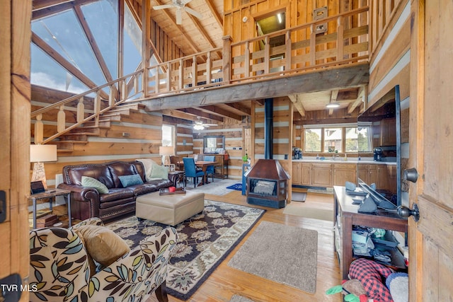 2390 W Allens Bridge Rd, Greeneville, TN 37743 - living room featuring a wood stove, a ceiling fan, light wood-type flooring, wooden walls, and stairs