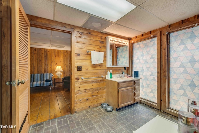 2390 W Allens Bridge Rd, Greeneville, TN 37743 - bathroom featuring wood walls, a drop ceiling, vanity, and brick patterned flooring