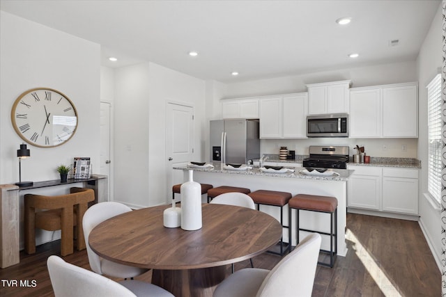 kitchen featuring white cabinetry, light stone countertops, a center island with sink, and appliances with stainless steel finishes