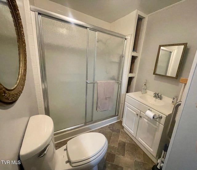 full bathroom featuring toilet, a stall shower, stone finish floor, and vanity