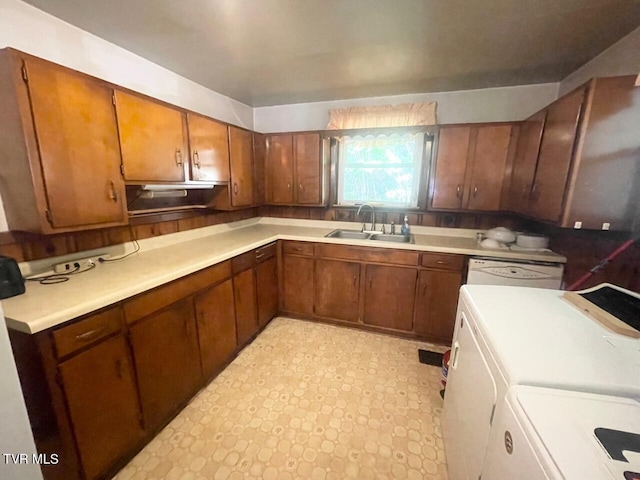 kitchen featuring brown cabinetry, white dishwasher, light countertops, separate washer and dryer, and a sink