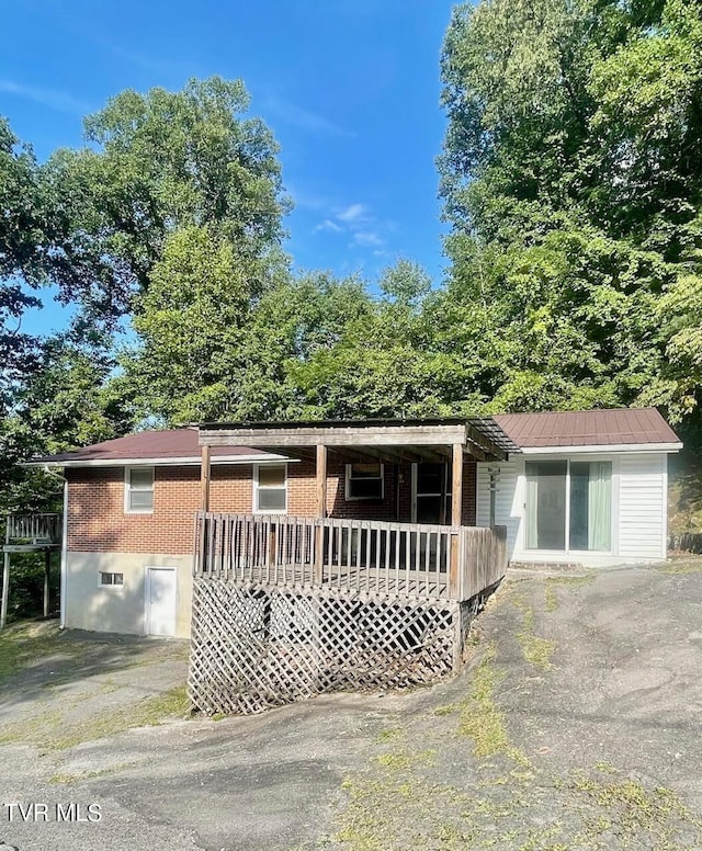 single story home featuring brick siding, driveway, and a deck