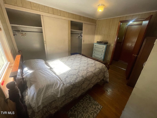 bedroom featuring crown molding, dark wood-style flooring, a closet, and wooden walls