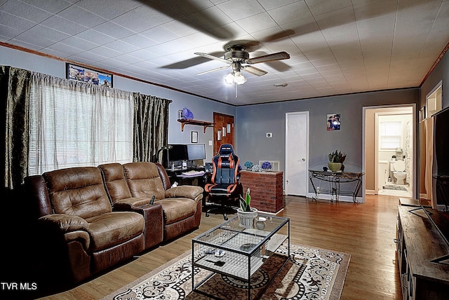 living room with ornamental molding, baseboards, a ceiling fan, and wood finished floors