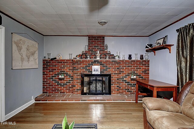 unfurnished living room featuring hardwood / wood-style flooring, a brick fireplace, and ornamental molding