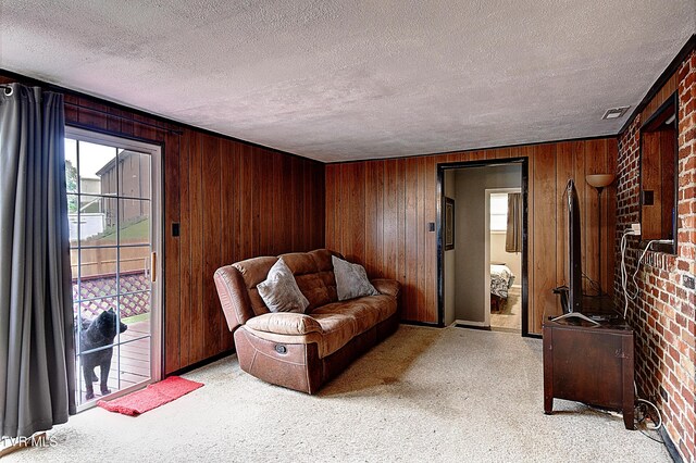 living area featuring light carpet, wood walls, a textured ceiling, and plenty of natural light