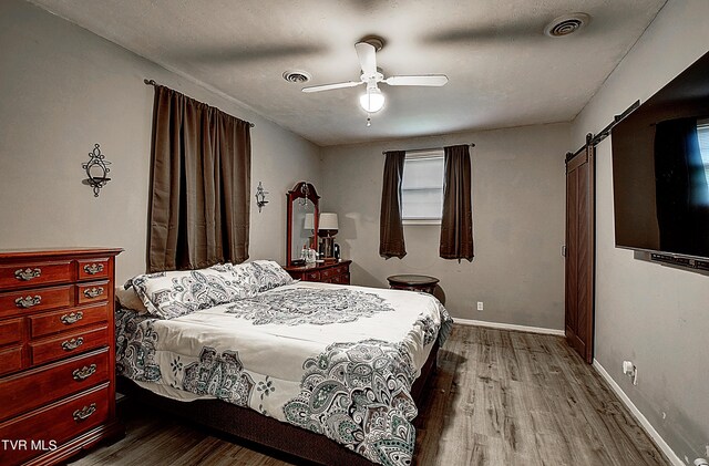 bedroom featuring ceiling fan, hardwood / wood-style flooring, and a barn door