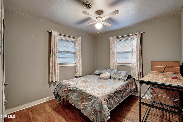 bedroom with visible vents, multiple windows, baseboards, and wood finished floors