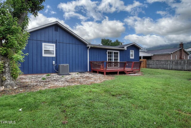 rear view of house with a yard, central AC unit, and a wooden deck