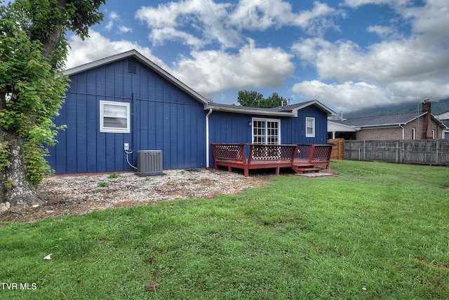 back of house featuring board and batten siding, fence, a lawn, cooling unit, and a deck