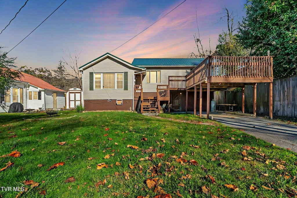 back house at dusk with a yard, a wooden deck, and a storage shed