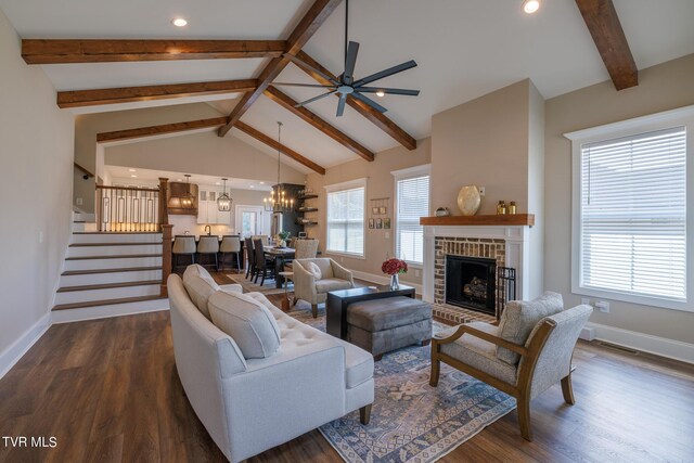 living room featuring dark hardwood / wood-style floors, high vaulted ceiling, ceiling fan with notable chandelier, beam ceiling, and a fireplace