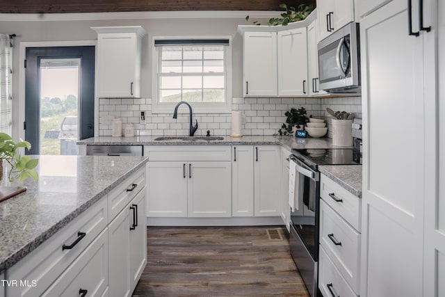 kitchen featuring dark wood-type flooring, sink, white cabinetry, stainless steel appliances, and backsplash