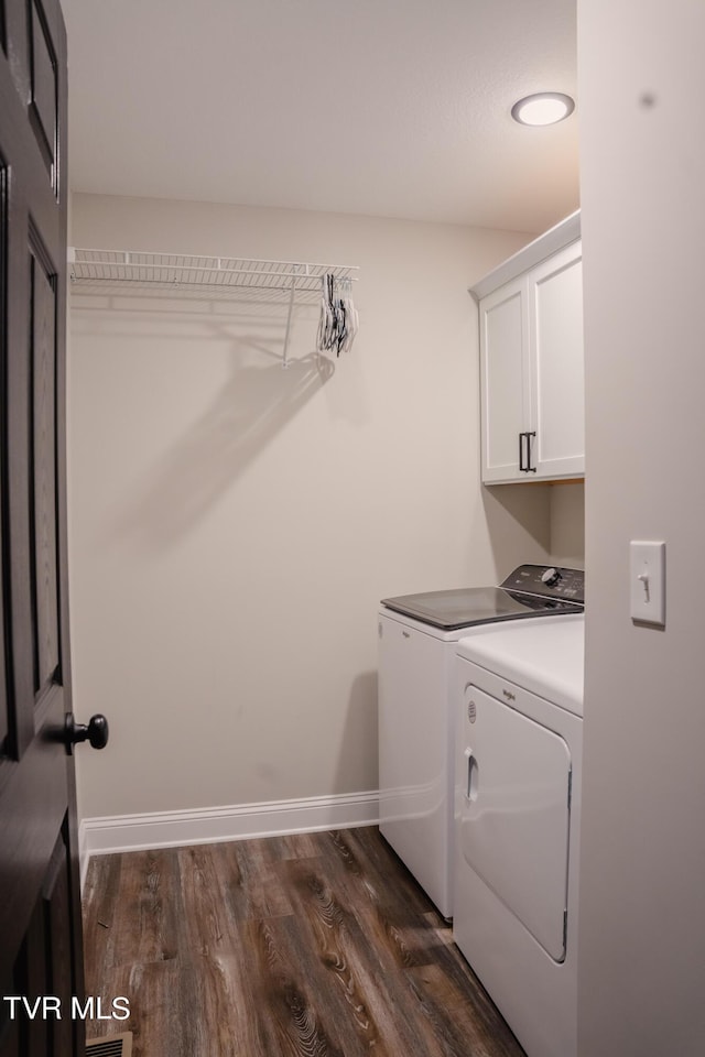 laundry room featuring washer and dryer, dark hardwood / wood-style floors, and cabinets