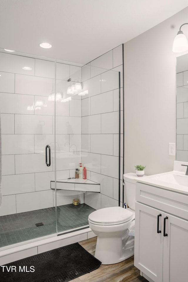 bathroom featuring toilet, vanity, walk in shower, and wood-type flooring