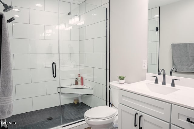 bathroom featuring vanity, a shower with shower door, and toilet