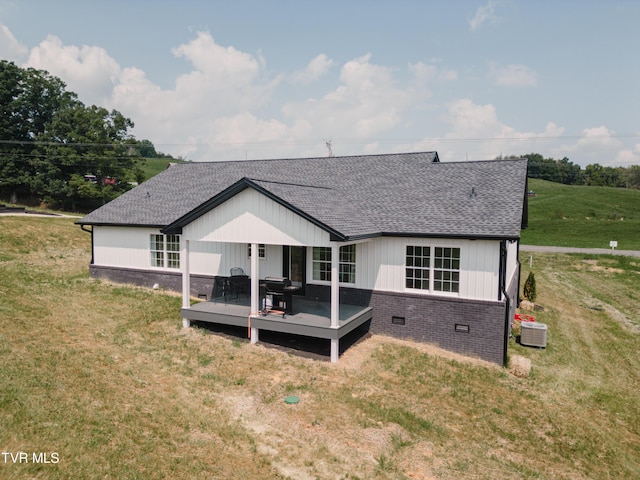 back of house featuring central AC, a deck, and a lawn