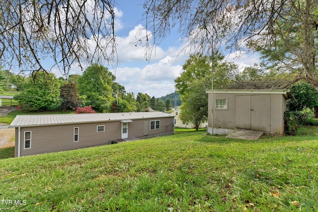 rear view of house featuring metal roof, a yard, a storage unit, and an outdoor structure