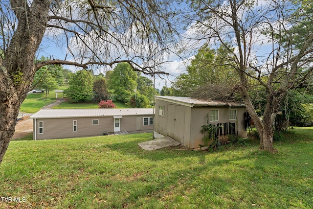 rear view of property with metal roof and a yard