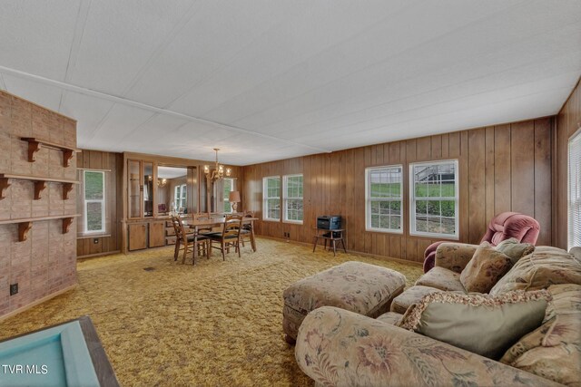 carpeted living room with wood walls and a notable chandelier