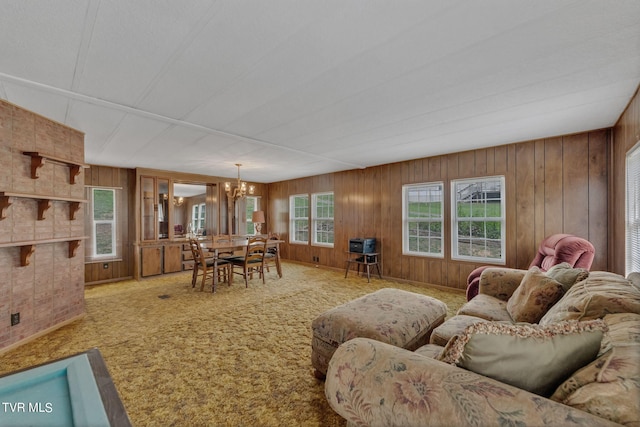 carpeted living area featuring wooden walls and an inviting chandelier