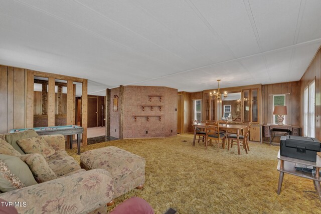 living room featuring wood walls, carpet, and a notable chandelier