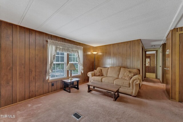 carpeted living room featuring wood walls and a textured ceiling