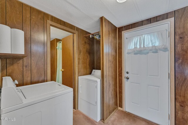 laundry area featuring independent washer and dryer, wooden walls, and light carpet