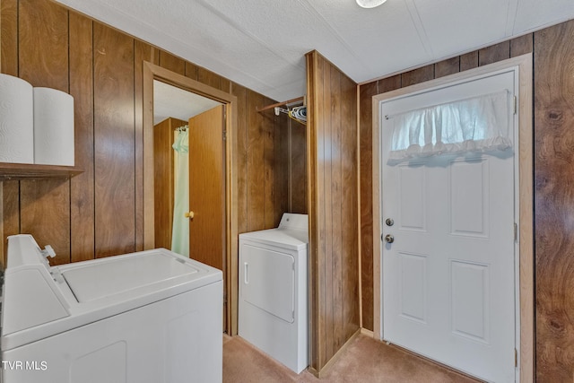 clothes washing area featuring laundry area, light carpet, independent washer and dryer, and wood walls