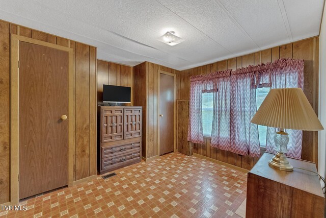 interior space with wood walls, a textured ceiling, and tile patterned flooring