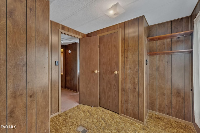 hall featuring light carpet and wood walls