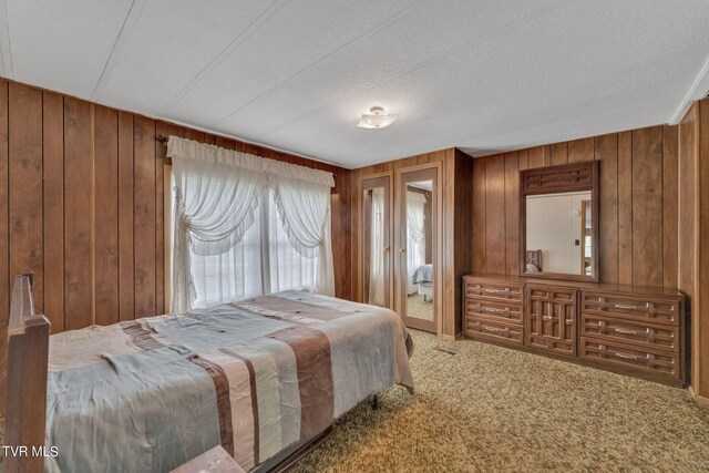 bedroom with wooden walls, a textured ceiling, and carpet floors