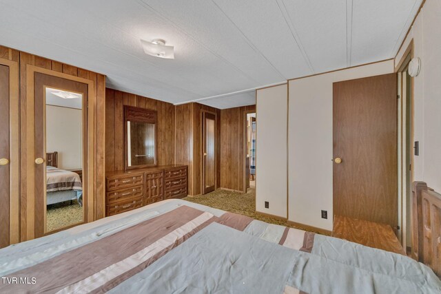 carpeted bedroom featuring wooden walls