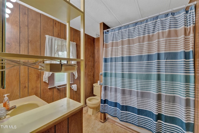 bathroom with toilet, wood walls, and a sink