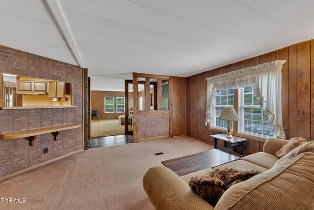 carpeted living room featuring wooden walls and a textured ceiling