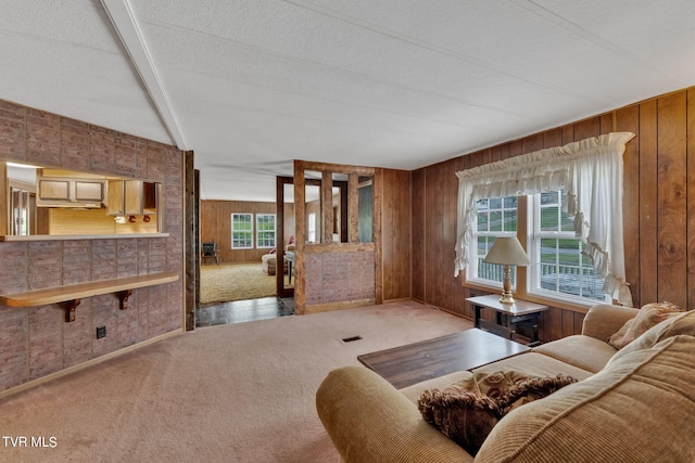 carpeted living room with vaulted ceiling with beams, wood walls, and a textured ceiling