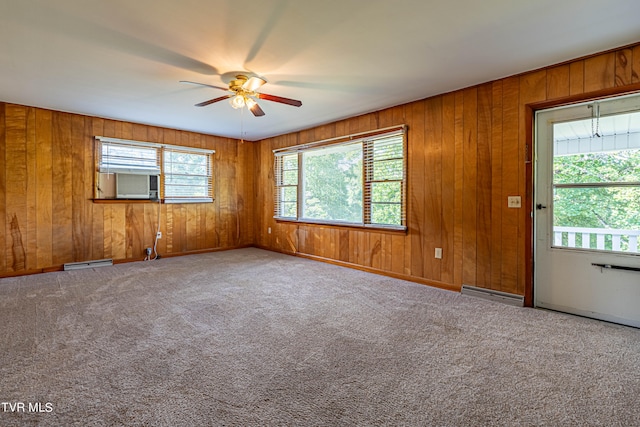 carpeted spare room featuring ceiling fan, wooden walls, and baseboard heating