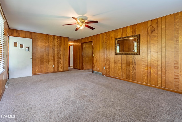 spare room with carpet floors, ceiling fan, and wooden walls