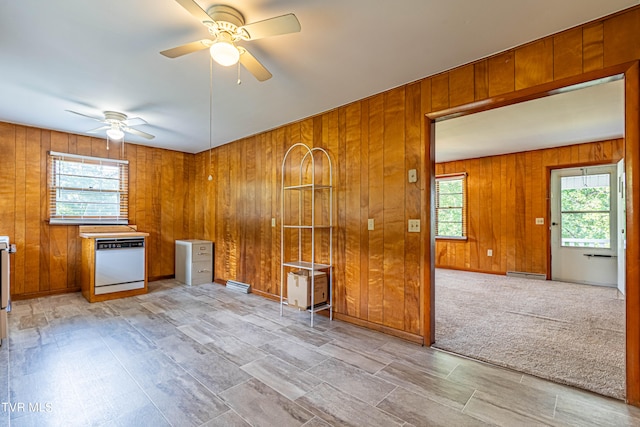 empty room featuring ceiling fan, light carpet, and wood walls