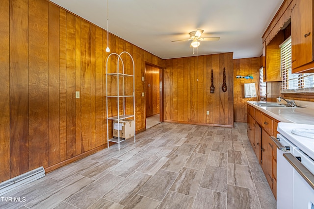 kitchen featuring ceiling fan, wood walls, sink, and stove