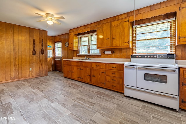 kitchen with sink, white range with electric stovetop, wooden walls, light tile patterned floors, and ceiling fan