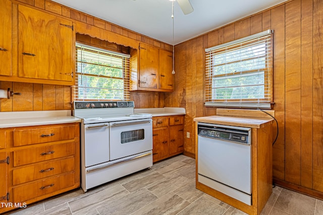 kitchen featuring a wealth of natural light, white appliances, ceiling fan, and wood walls