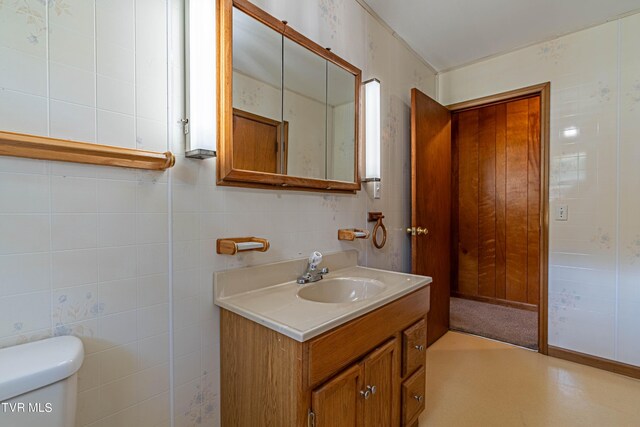 bathroom with tile walls, vanity, and toilet