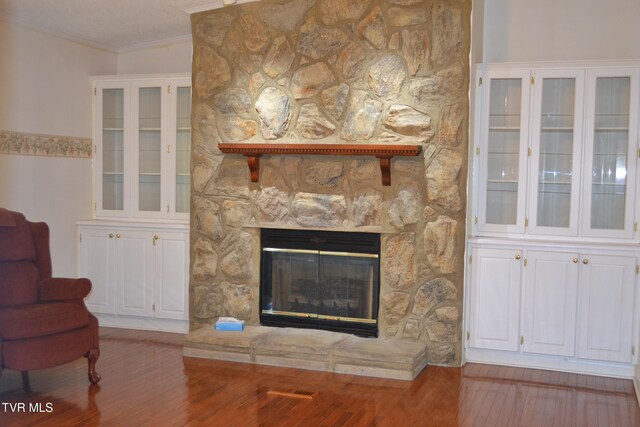 unfurnished living room featuring a stone fireplace, hardwood / wood-style flooring, and ornamental molding