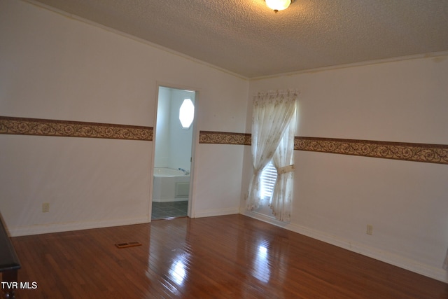 unfurnished room featuring hardwood / wood-style floors, a textured ceiling, vaulted ceiling, and crown molding