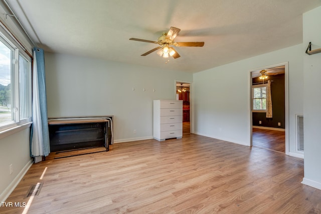 unfurnished bedroom featuring ceiling fan, multiple windows, and light wood-type flooring