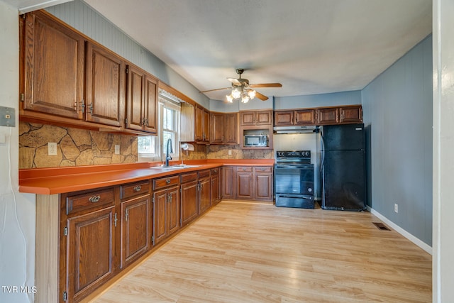 kitchen with sink, light hardwood / wood-style flooring, black appliances, and backsplash