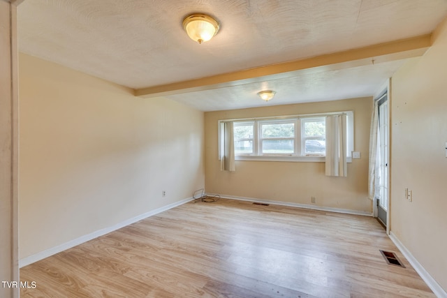 empty room featuring light hardwood / wood-style floors and beam ceiling