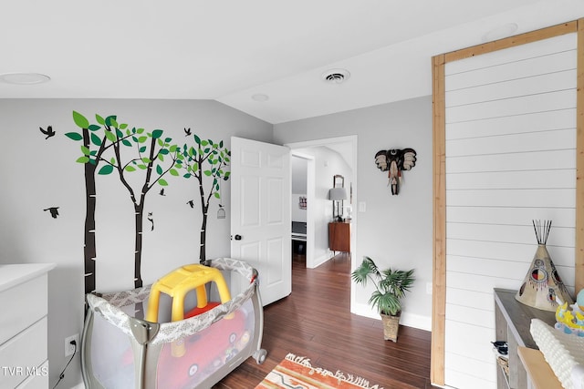 interior space with dark wood-style floors, vaulted ceiling, visible vents, and baseboards